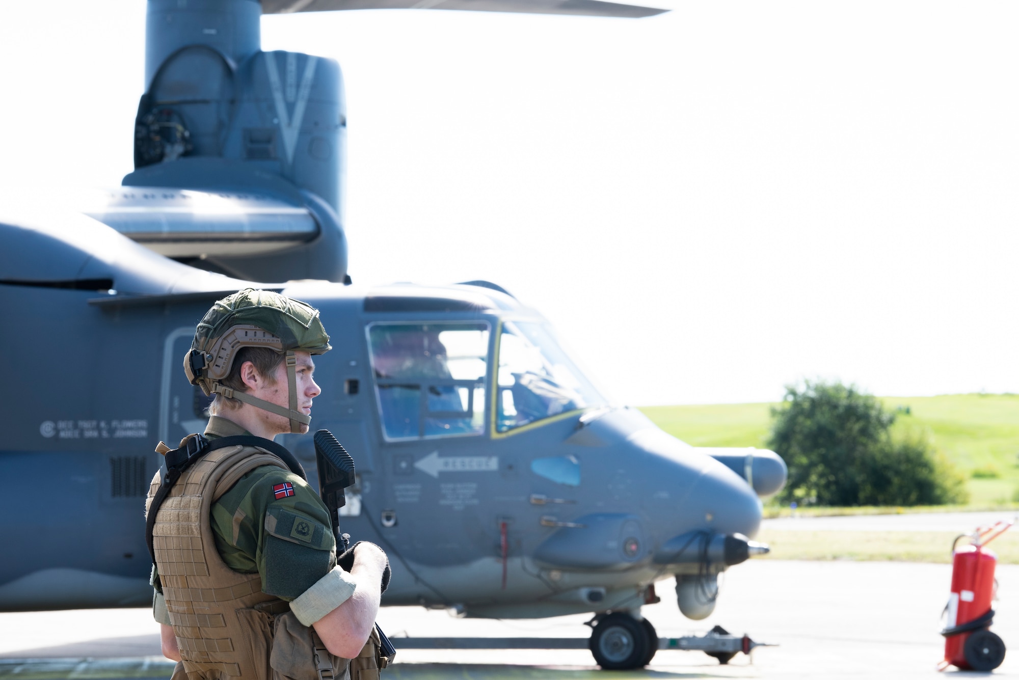 A Norwegian military member stands guard in front of a CV-22B Osprey, based out of RAF Milden-hall, U.K., during a training mission at Rygge Air Station, Norway, August 25, 2020. Integration with the Norwegian Air Force allowed the 352d Special Operations Wing to enhance and strengthen bonds with our partner nation and further secure the strategic high-north region. The exercise provided train-ing for 352d Special Operations Wing members on capabilities such as personnel recovery, forward area refueling point, aerial refueling, maritime craft delivery system, and fast rope training. (U.S. Air Force photo by Staff Sgt. Michael Washburn)
