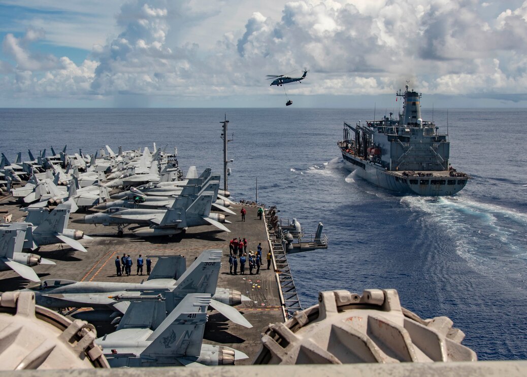 The Navy's only forward-deployed aircraft carrier USS Ronald Reagan (CVN 76) approaches fleet replenishment oiler USNS John Ericsson (T-AO 194) as an MH-60S Sea Hawk, attached to the "Golden Falcons" of Helicopter Sea Combat Squadron (HSC) 12, transports cargo during a replenishment-at-sea.