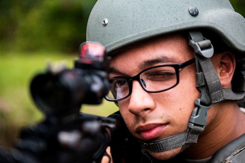 Photo of Airman looking down the sights of an M4 carbine.