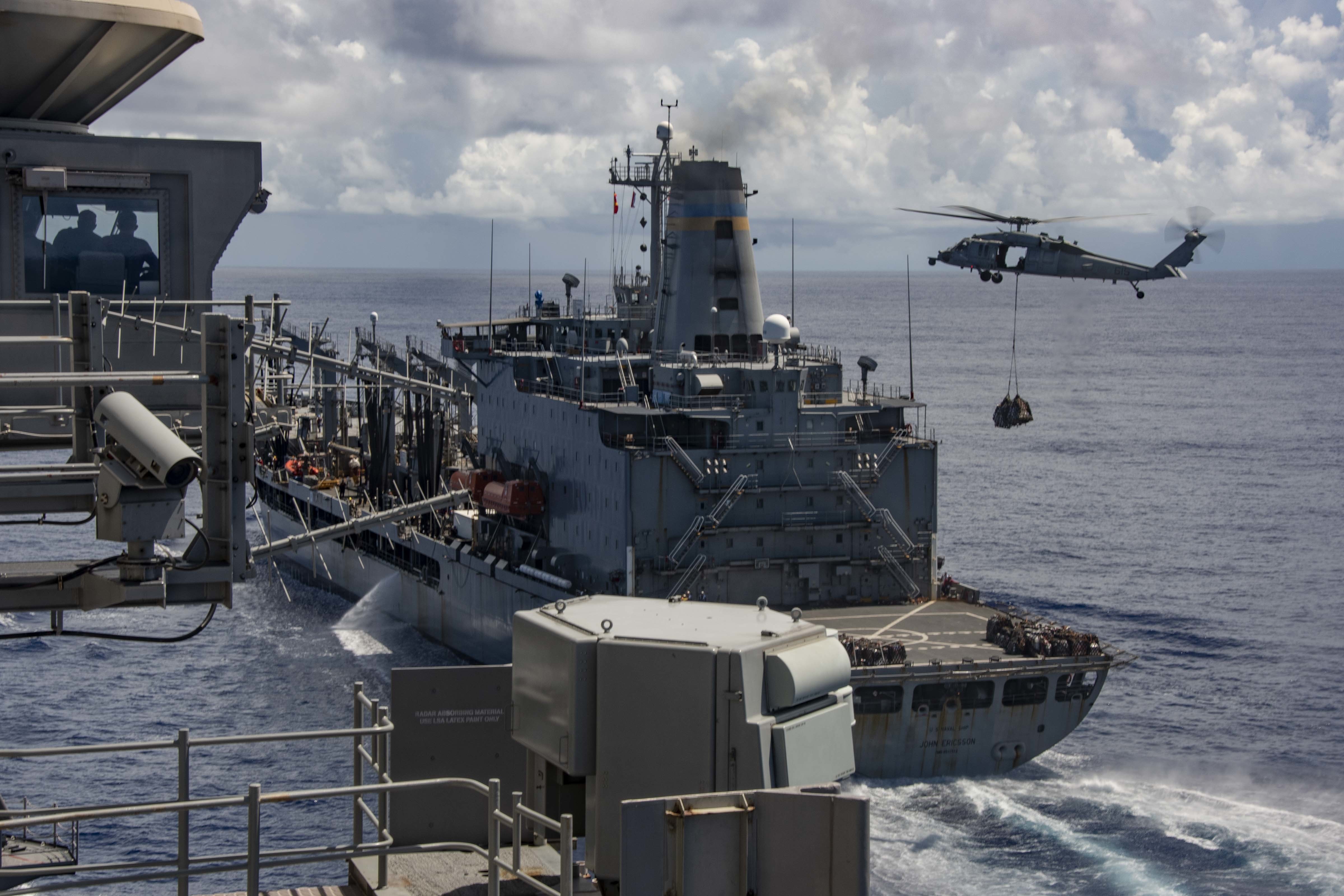 The Navy's only forward-deployed aircraft carrier USS Ronald Reagan (CVN 76) approaches fleet replenishment oiler USNS John Ericsson (T-AO 194) as an MH-60S Sea Hawk, attached to the "Golden Falcons" of Helicopter Sea Combat Squadron (HSC) 12, transports cargo during a replenishment-at-sea.