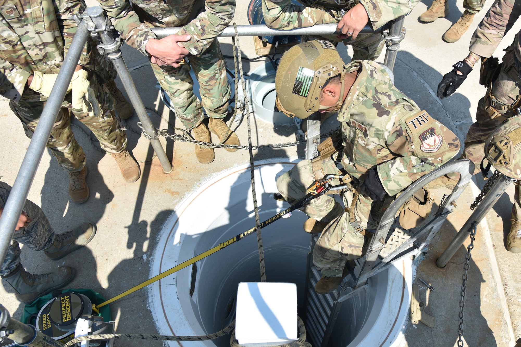 An Airman is at the top of a ladder, descending into a shaftway into a launch facility.