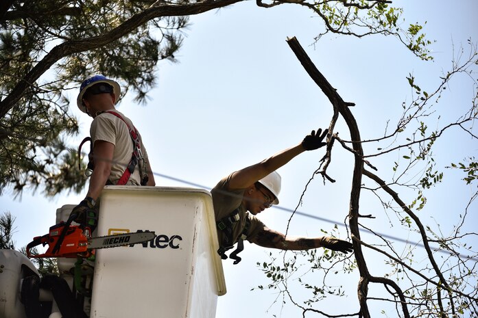 Staff Sgt. Bobby Breland, 8th Civil Engineer Squadron heavy equipment and pavement craftsman, and Senior Airman Keith Robinson, 8th CES electrical systems shop remove tree branches during typhoon recovery operations at Kunsan Air Base, Republic of Korea, Sept. 3, 2020.
