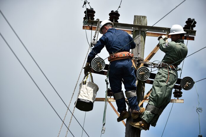 Tech. Sgt. Chaz Lineberger and Senior Airman Cody McCormick 8th Civil Engineer Squadron electrical systems technicians, prepare a line for reattachment in response to Typhoon Maysak at Kunsan Air Base, Republic of Korea, Sept. 3, 2020.