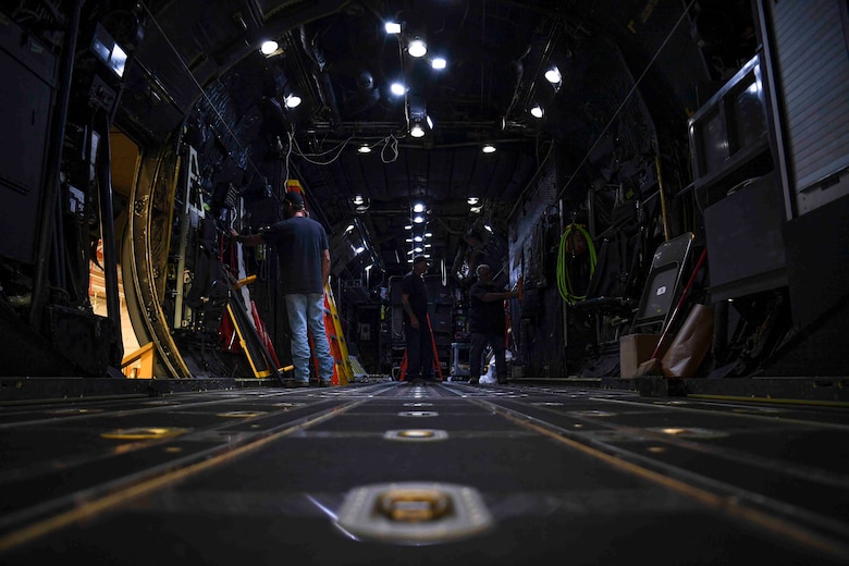 Men working on the inside of a large military aircraft