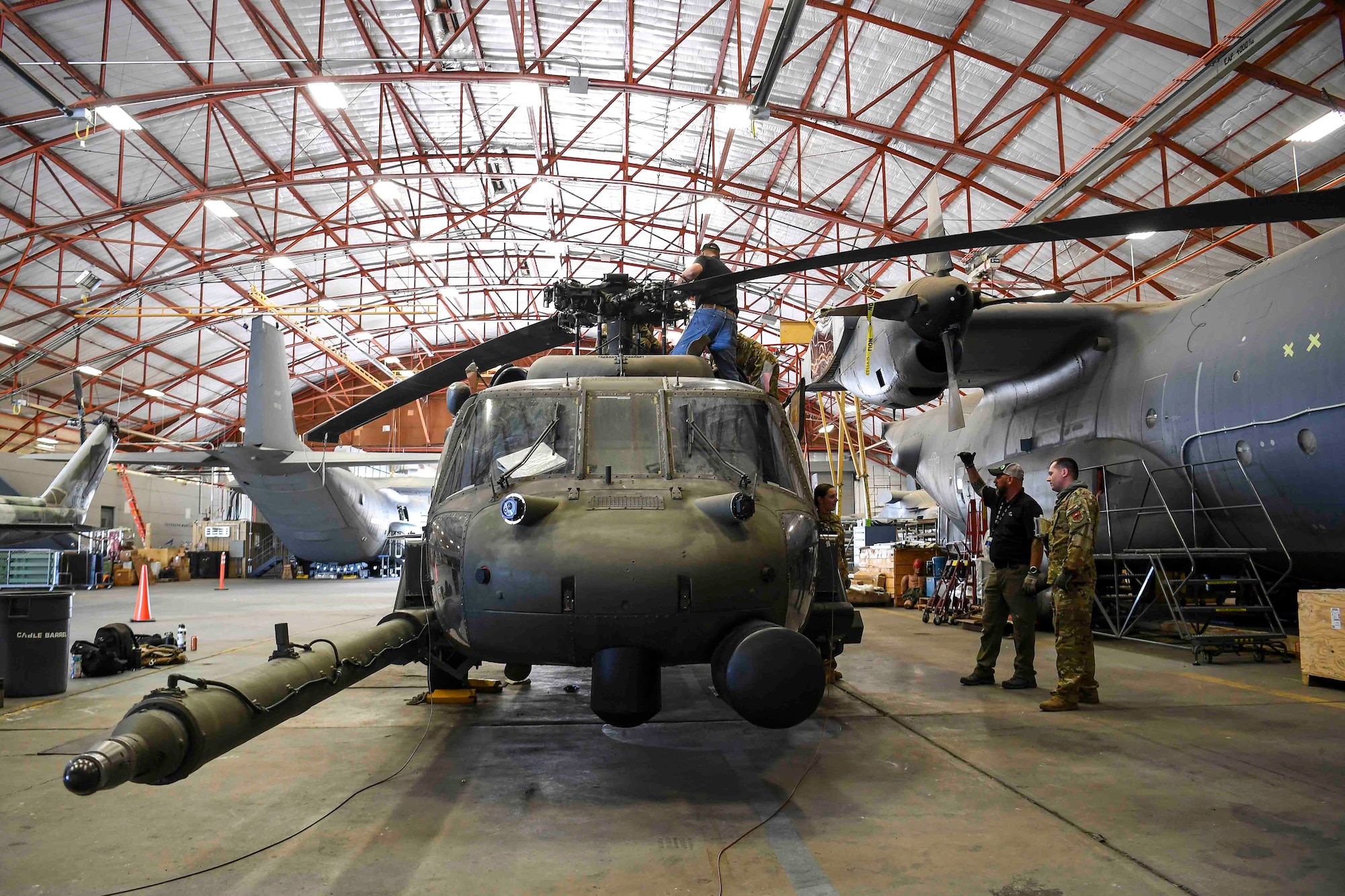 Men standing around a military helicopter that is in maintenance