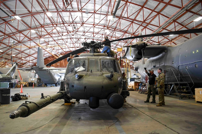 Men standing around a military helicopter that is in maintenance