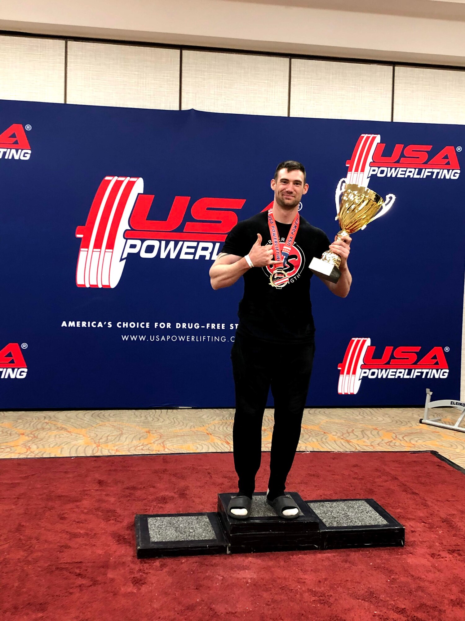 Senior Airman Dalton McIntire, a Scientific Applications Specialist at the Air Force Technical Applications Center, Patrick AFB, Fla., displays the coveted hardware he received during a powerlifting competition, at which he took first place. McIntire hopes to encourage more Airmen to get involved in powerlifting.  (Courtesy photo)