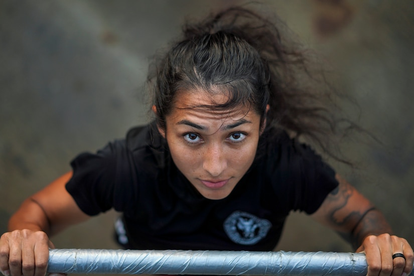 A sailor, shown from above, holds a barbell while exercising.