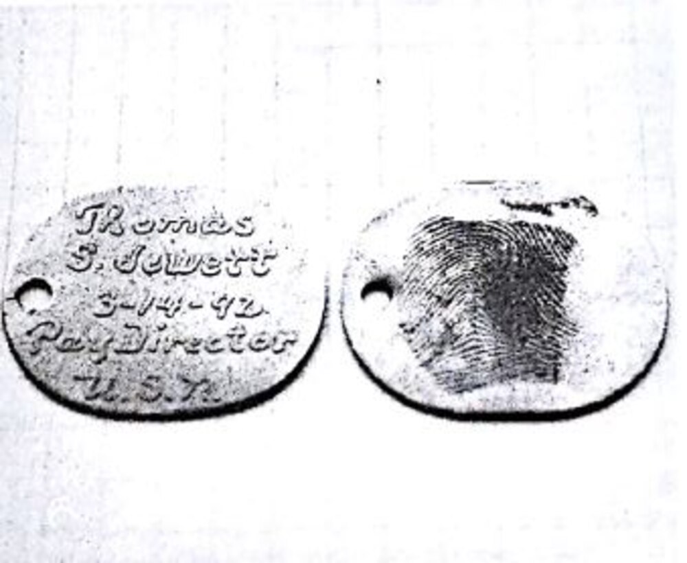 Two dog tags are displayed; one shows writing while the other shows a fingerprint.