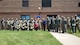 28 Military members, in uniform, pose for a group photo with the Secretary of the Air Force, Barbara Barrett, outside on the grass next to the squadron building.