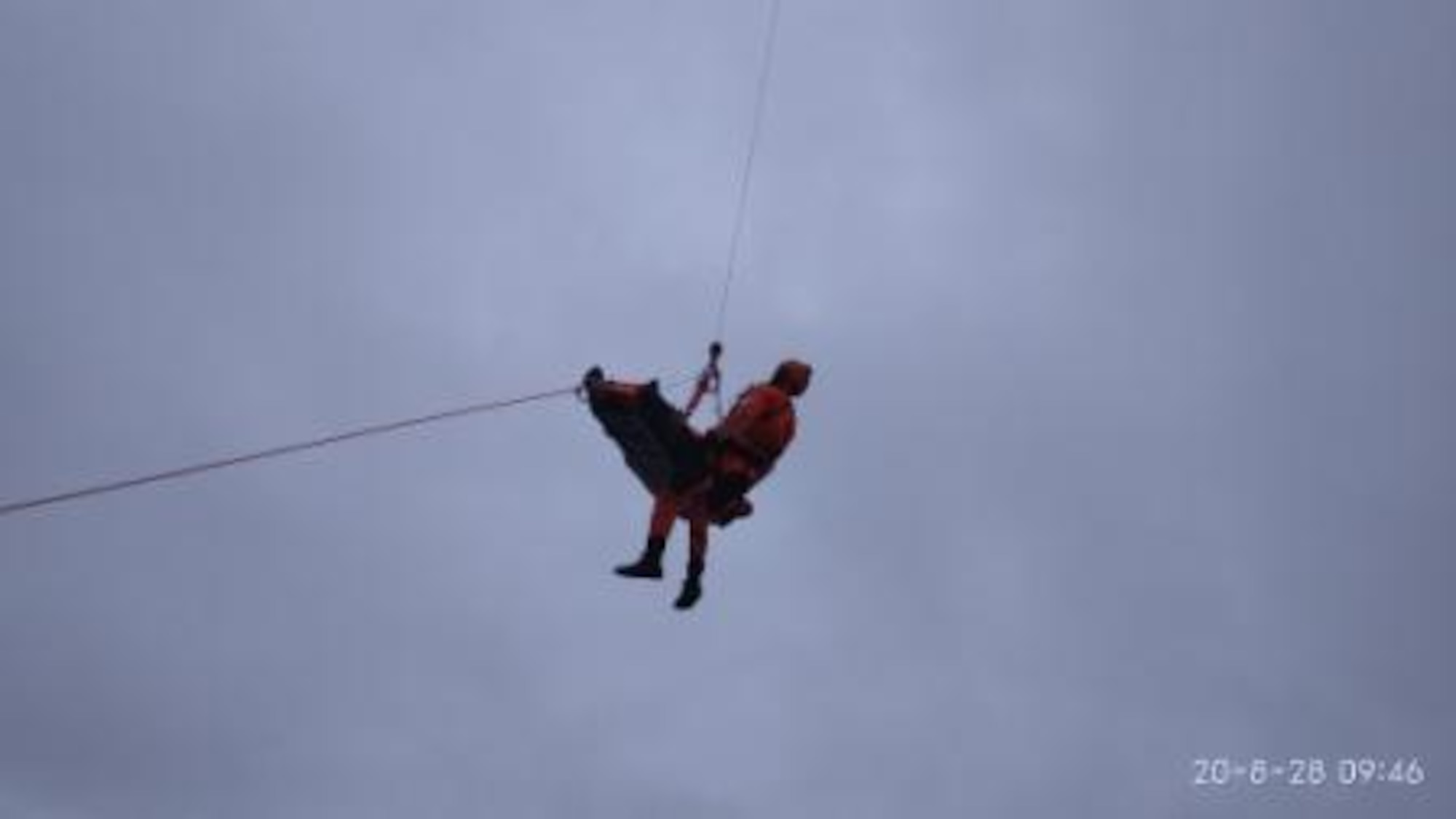 A Coast Guard Search & Rescue specialist accompanies an injured sailor from sea to air Aug. 26, 2020, more than 1,000 miles off the coast of California.