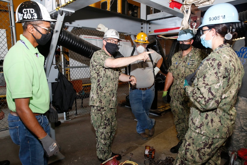 A Navy officer speaks with shipyard workers.