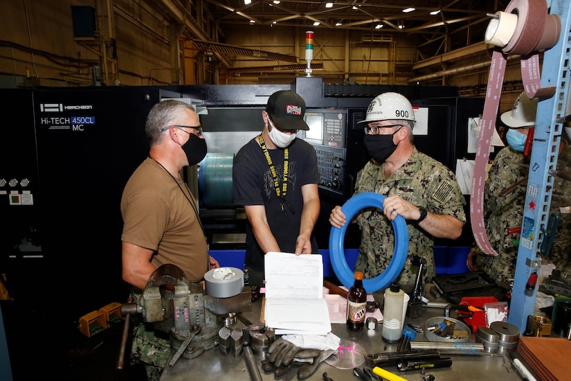 A Navy officer speaks with shipyard workers.