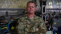 Senior Master Sgt. Christopher Haney poses in front of a jet engine at Joint Base Langley-Eustis, Virginia, July 20, 2020.