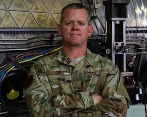 Senior Master Sgt. Christopher A. Haney poses in front of a jet engine at Joint Base Langley-Eustis, Virginia, July 20, 2020.