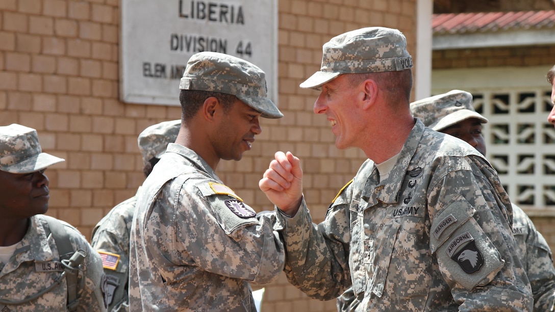 Joint Forces Command–United Assistance commander Major General Gary Volesky, right, elbow bumps Sergeant 1st Class Roderick Davis, logistics section noncommissioned officer in charge, 129th Combat Sustainment Support Battalion, 101st Sustainment Brigade, Task Force Lifeliner, during visit to Monrovia, Liberia, November 6, 2014 (U.S. Army/Mary Rose Mittlesteadt)