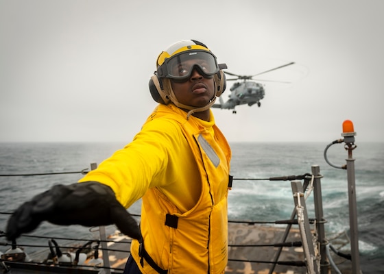 Sailor directs MH-60 Sea Hawk helicopter assigned to “Warlords” of Helicopter Maritime Strike Squadron 51 as it takes off on flight deck aboard USS McCampbell during vertical replenishment training, East China Sea, March 27, 2020 (U.S. Navy/Markus Castaneda)