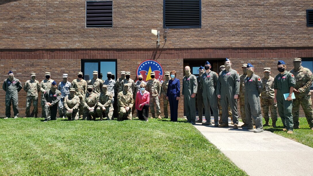 28 Military members, in uniform, pose for a group photo with the Secretary of the Air Force, Barbara Barrett, outside on the grass next to the squadron building.