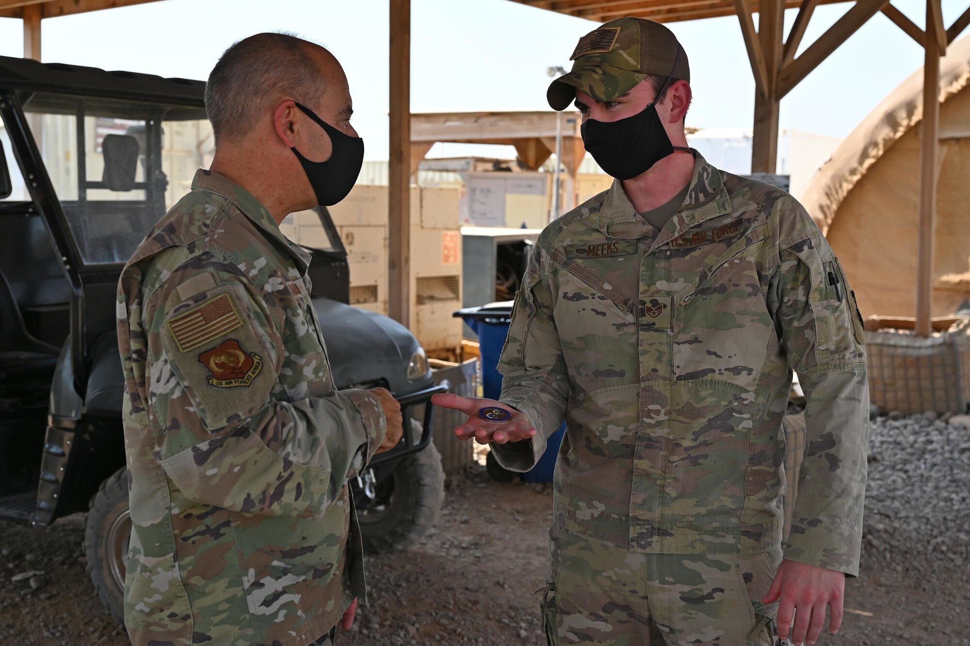 U.S. Air Force Gen. Jeffrey L. Harrigian, U.S. Air Forces in Europe and Air Forces Africa commander, coins Staff Sgt. Carson Meeks, 12th Expeditionary Operations Squadron ground systems operator, at an airfield in East Africa, September 3, 2020. Harrigian visited with U.S. Air Force members in Djibouti and East Africa to gain insight into their integrated missions, and the multiple roles of Airmen in the joint environment. (U.S. Air Force photo by Staff Sgt. Dana J. Cable)
