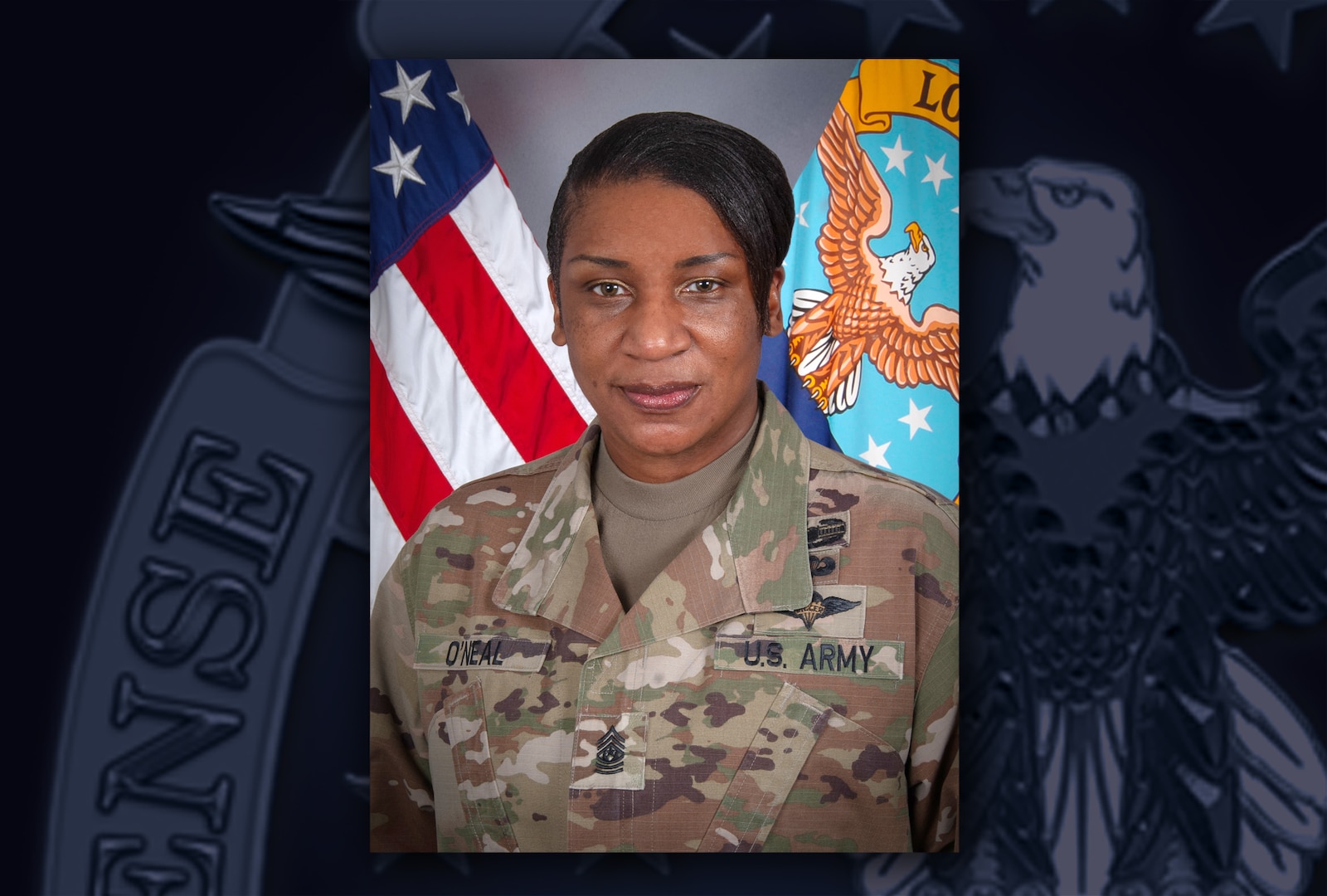 Female Army Command Sgt. Major in front of flags.