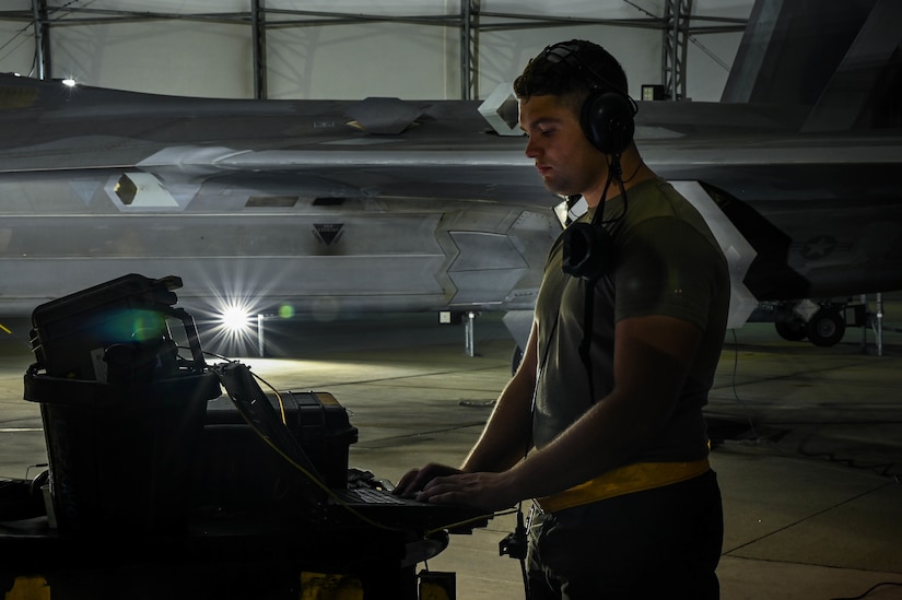 A man stands at a computer with a large aircraft in the background.