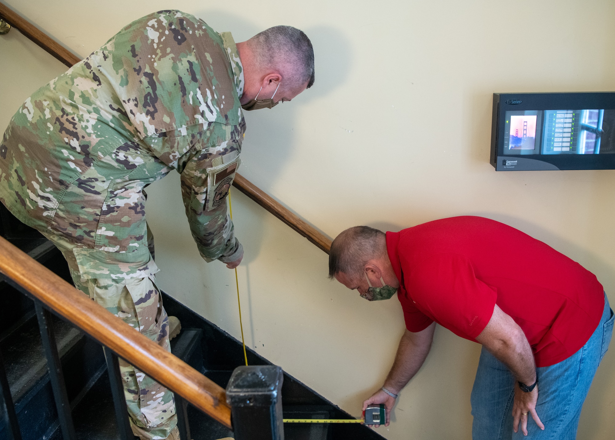 Two men measure staircase steps.