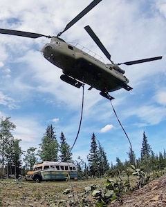 Alaska Army National Guard Soldiers assigned to 1st Battalion, 207th Aviation Regiment execute an extraction mission via a CH-47 Chinook helicopter over Healy, Alaska, June 18, 2020. As part of a combined effort with the Department of Natural Resources, the Guardsmen rigged and airlifted “Bus 142”,, an historic icon from book and film, “Into the Wild”, out of its location on Stampede Road in light of public safety concerns. The bus will be stored at a secure site while the DNR considers all options and alternatives for its permanent disposition. (Alaska National Guard courtesy photo)