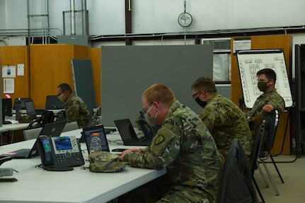 Alaska Army National Guard Soldiers are separated into forward operating sites by tables and dividers during this exercise, to replicate the separation they will face while In Poland during a training exercise at Fort Hood, Texas, May 25, 2020. Simulated separation will force them to contact other locations via. email or telephone.  (U.S. Army National Guard Photo by SGT Heidi Kroll)