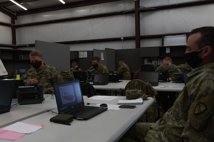 Alaska Army National Guard Soldiers are separated into forward operating sites by tables and dividers during this exercise, to replicate the separation they will face while In Poland during a training exercise at Fort Hood, Texas, May 25, 2020. Simulated separation will force them to contact other locations via. email or telephone.  (U.S. Army National Guard Photo by SGT Heidi Kroll)