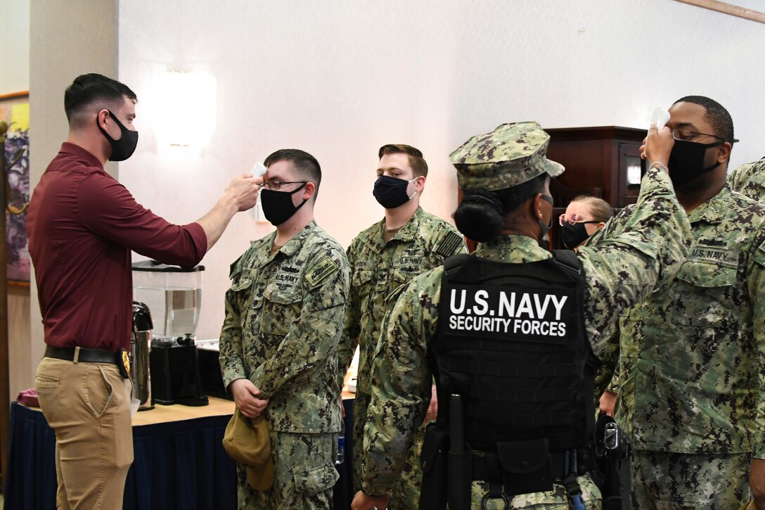 Sailors use a thermometer to  take other sailors' temperatures.