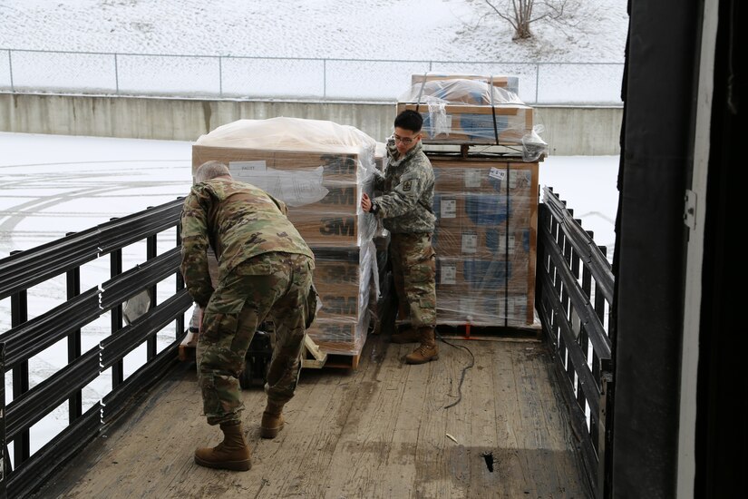 Alaska National Guard Soldiers Spc. Fred Ulroan and Pfc. Duane Chavis unload palets of COVID-19 supplies and personal protective equipment from the national stockpile at a warehouse in Anchorage in conjunction with the Department of Health and Human Services, Apr. 2, 2020. The Soldiers are on state active duty orders for the National's Guard's Quick Response Force assigned to the COVID-19 effort. (U.S. Army National Guard photo by Sgt. Seth LaCount/Released)