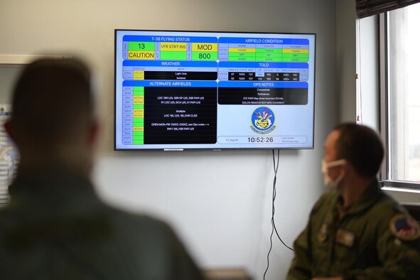 A pilot from the 50th Flying Training Squadron checking the airfield conditions at the step desk, August 28, 2020, on Columbus Air Force base, Miss. Pilots use the AF Status application readily available at the step-desk to check on weather conditions, alternate airfields and other pertinent information. (U.S. Air Force photo by Senior Airman Jake Jacobsen)