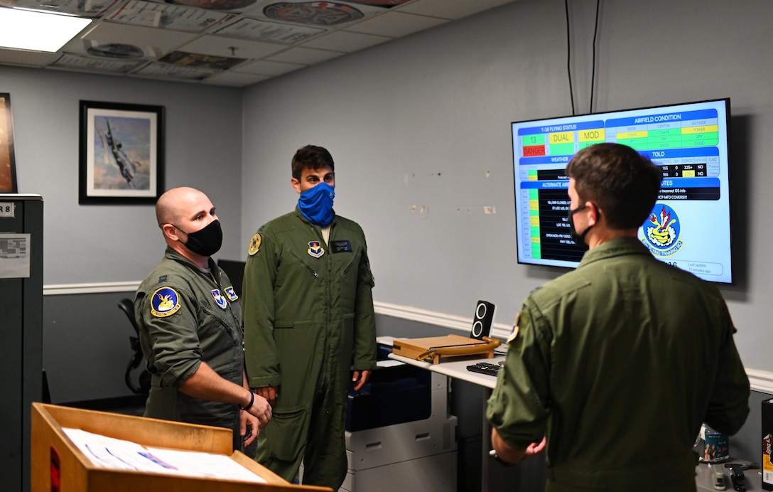 Capt. Mckenzie Kane (left), 50th Flying Training Squadron instructor pilot, Capt. Anthony Olive (middle), 50th FTS student pilot and Capt. Kirk Jaunich (right), 50th FTS student pilot discuss the benefits of the AF Status application August 24, 2020, on Columbus Air Force base, Miss. Along with the AF Status application Kane designed other programs that focus on helping pilots gather information in an easy to read and functional format way. (U.S. Air Force photo by Senior Airman Jake Jacobsen)