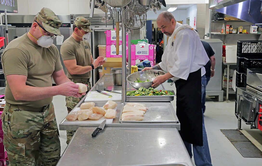 Alaska Army National Guard Soldiers Sgt. David Osmanson and Staff Sgt. Edward Jones, assigned to the AKARNG Recruiting and Retention Battalion work alongside Bean's Cafe employees, creating pre-packed lunches in the kitchen at Bean’s Cafe in Anchorage, Alaska, Apr. 8, 2020. This food will be distributed to thousands of local Alaskans sheltering at Sullivan and Boeke arenas as well as the Alaska After School Lunch program. (U.S. Army National Guard photo by Sgt. Seth LaCount/Released)