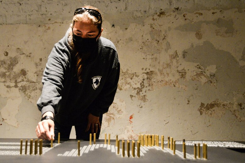U.S. Air Force Staff Sgt. Lisa Kiesewetter, 86th Security Forces Squadron military working dog trainer, places a bullet casing in the exhibit at former U.S. Army Ordnance Depot Maßweiler, Germany, Sept. 4, 2020. Each bullet casing pays tribute to animals who gave the ultimate sacrifice for their country. (U.S. Air Force photo by Tech. Sgt. J. Smith)