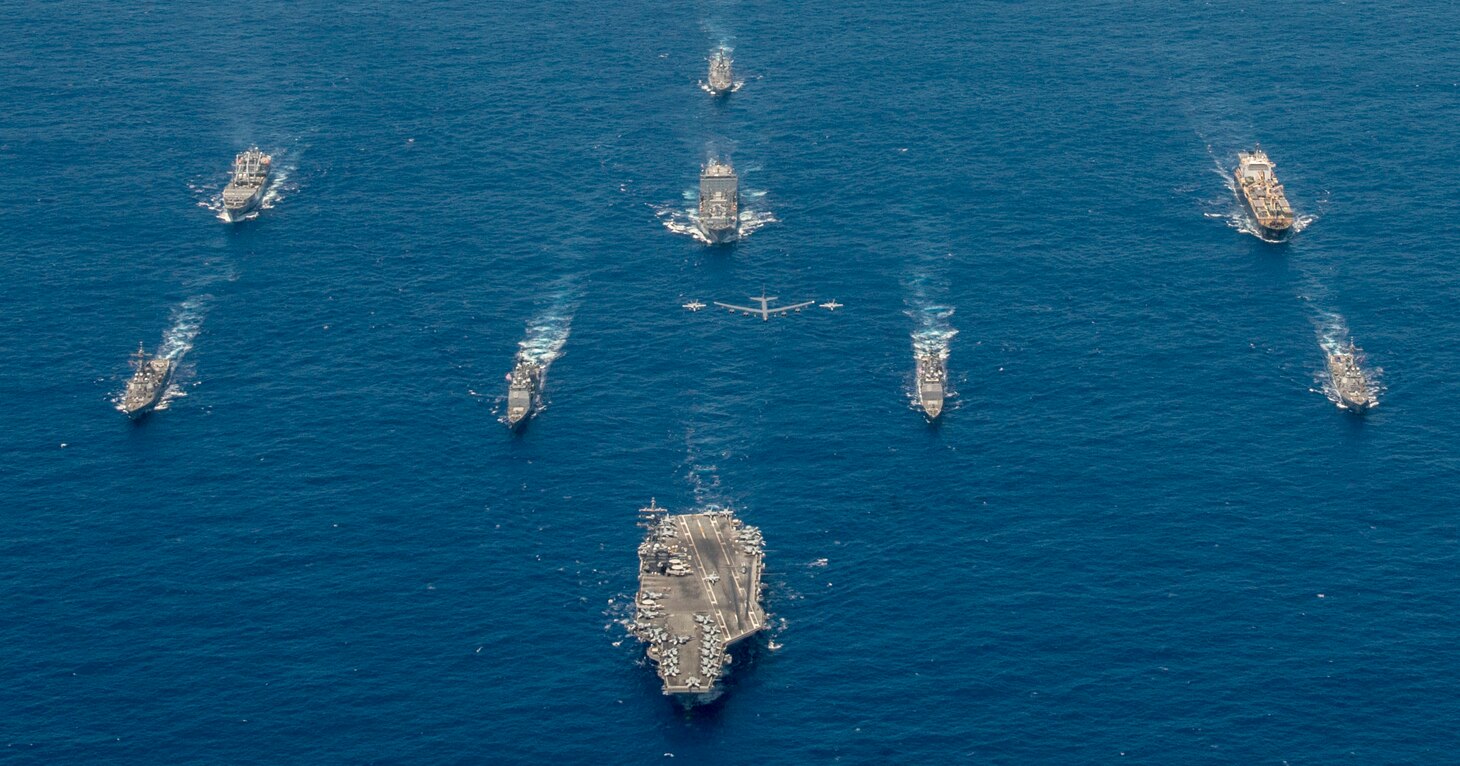 PHILIPPINE SEA (Sept. 17, 2018) USS Ronald Reagan (CVN 76) leads a formation of Carrier Strike Group Five ships as U.S. Air Force B-52 Stratofortress aircrafts and U.S. Navy F/A-18s pass overhead for a photo exercise during Valiant Shield 2018. The biennial, U.S. only, field-training exercise focuses on integration of joint training among the U.S. Navy, Air Force and Marine Corps. This is the seventh exercise in the Valiant Shield series that began in 2006. (U.S. Navy photo by Mass Communication Specialist 2nd Class Kaila Peters)