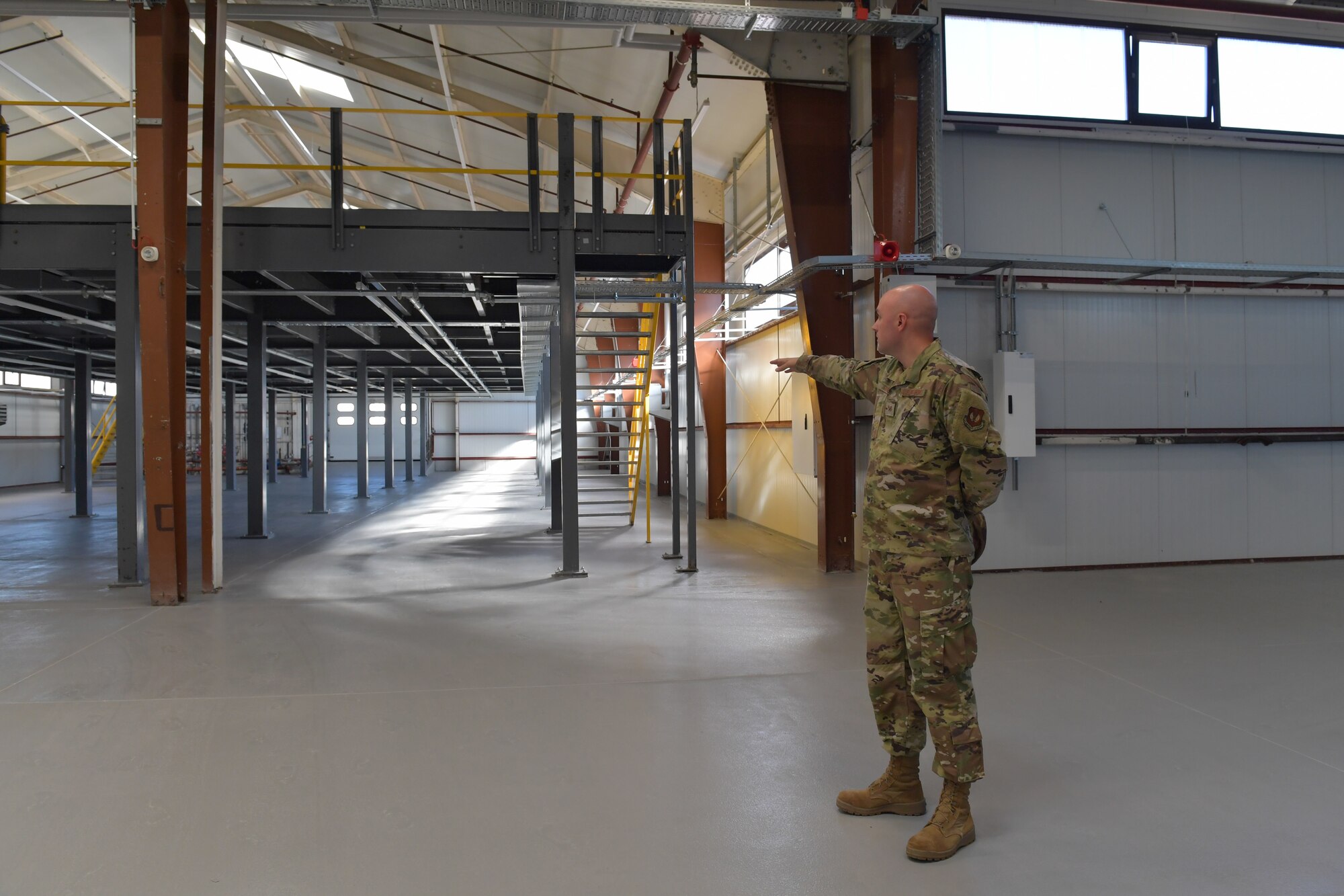 An Airman points to a mezzanine in a maintenance facility.