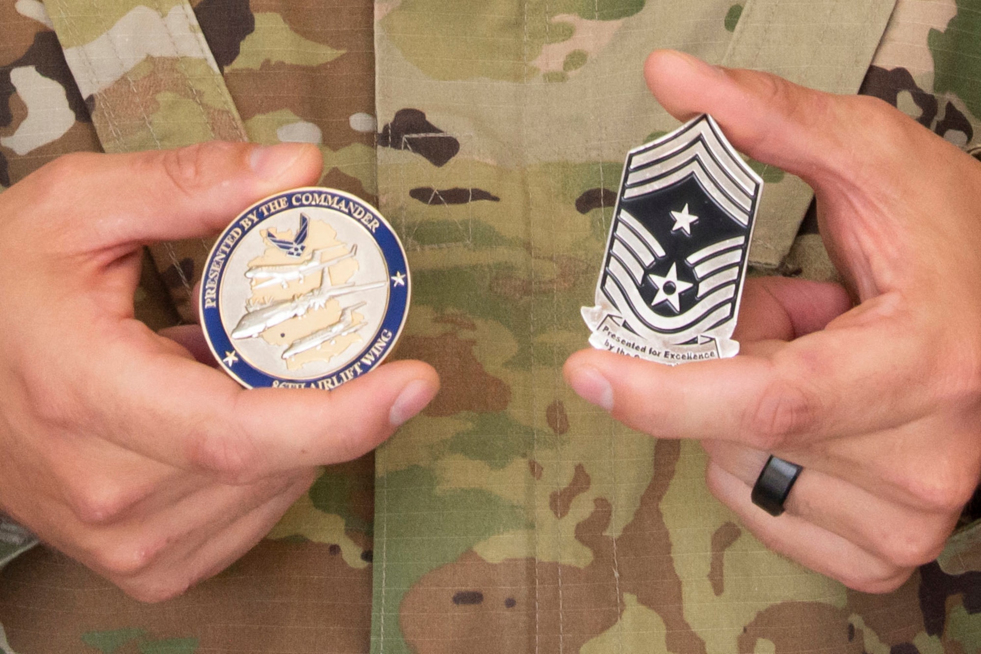 A close-up of two coins being held by an Airman.