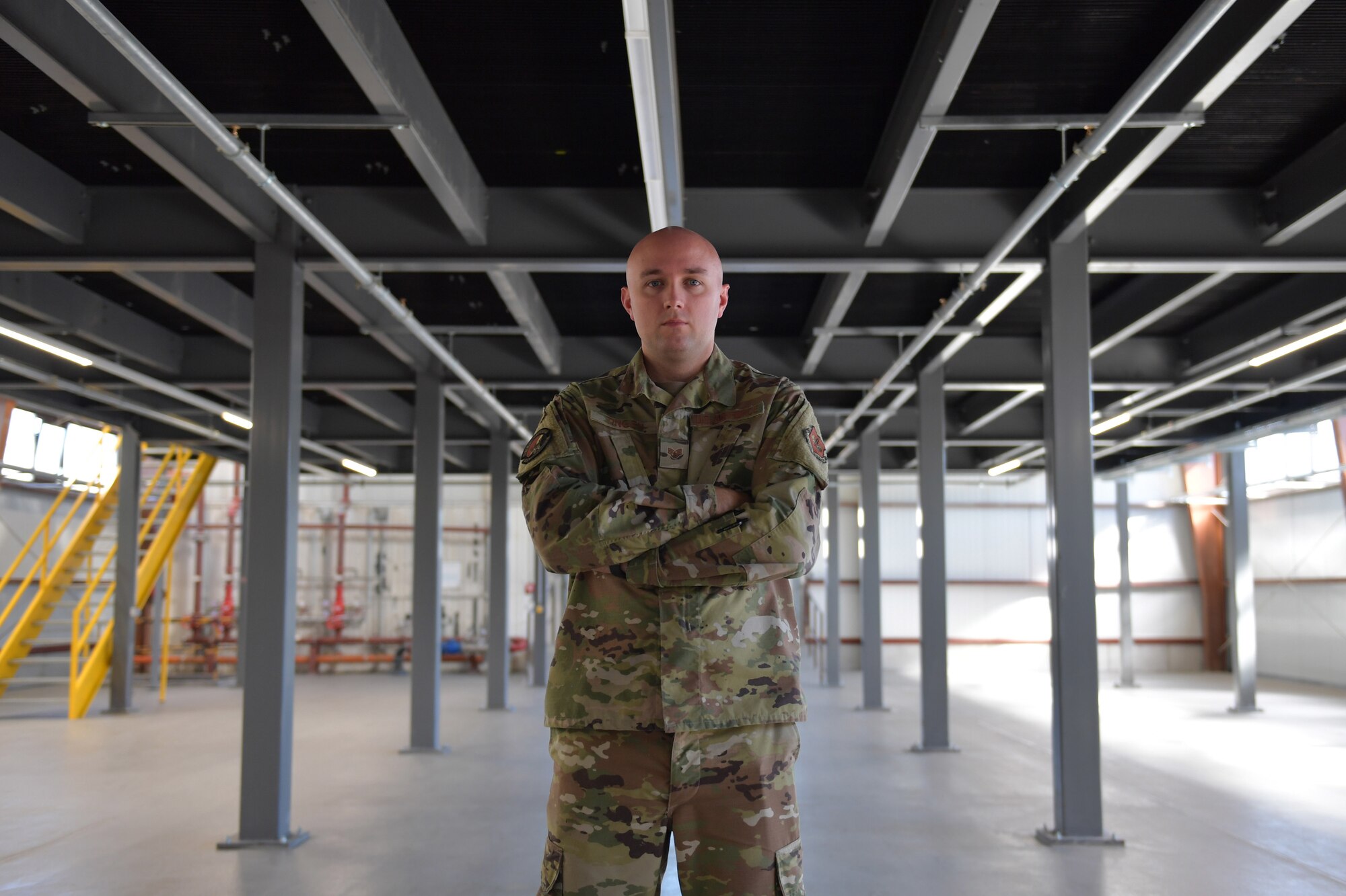 An Airman standing under a mezzanine in a warehouse.