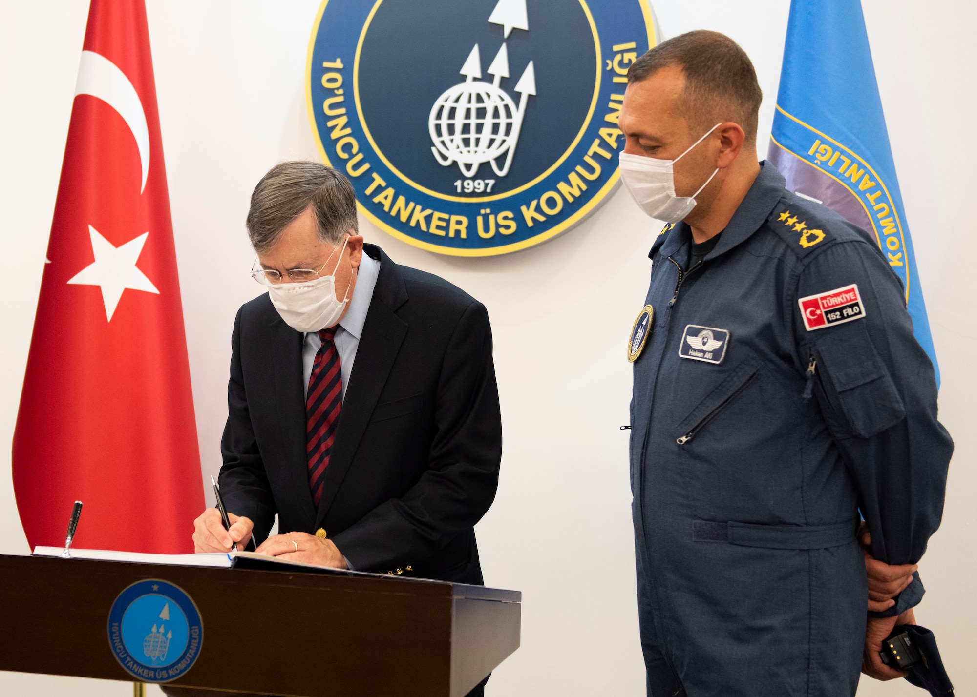 U.S. Ambassador to Turkey David Satterfield signs a guest book at the Turkish Command building while Turkish Air Force Col. Hakan Aki, 10th Tanker Wing chief of operations, watches.