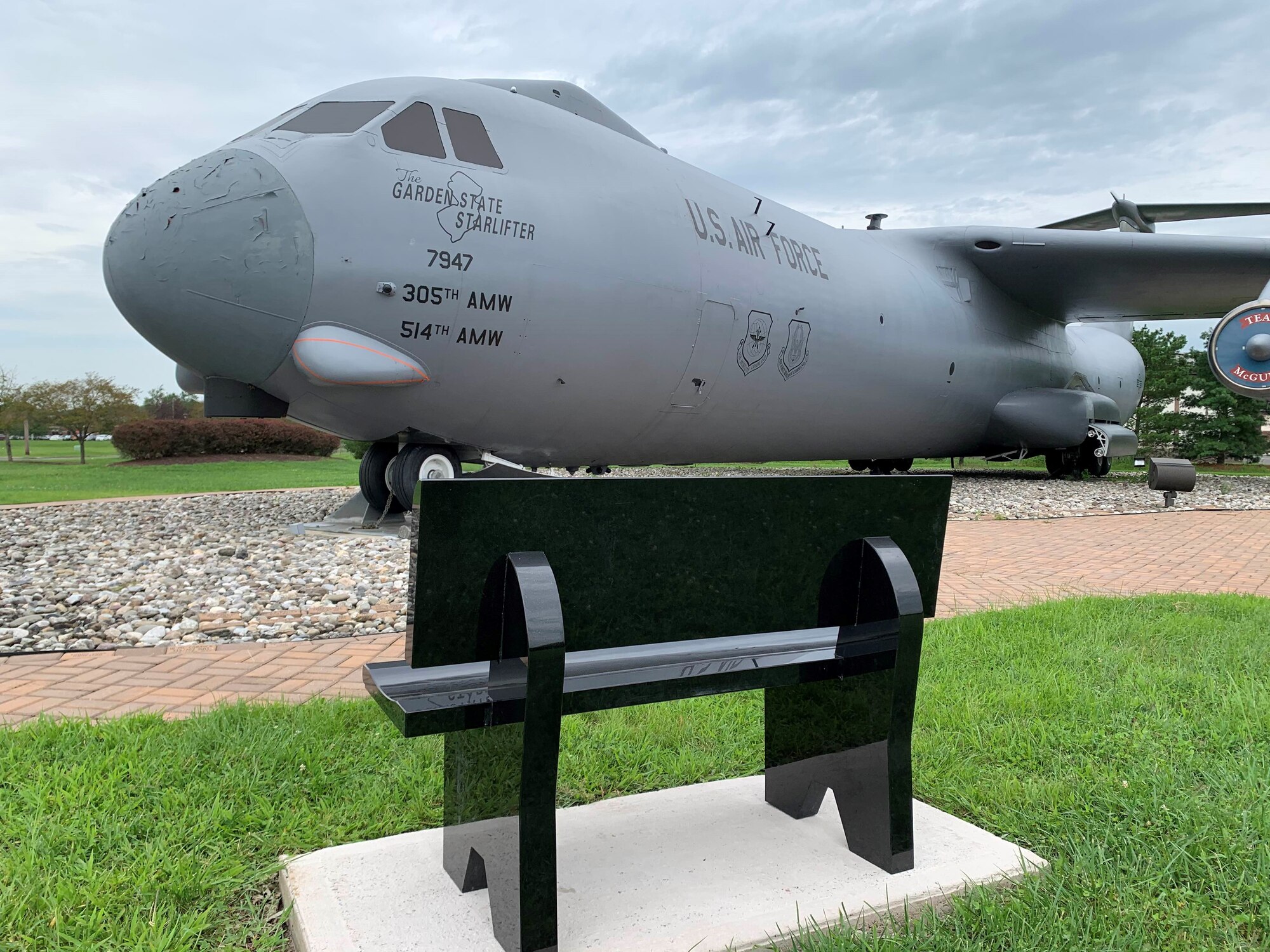 A photo of a granite bench in front of the Starlifter memorial.