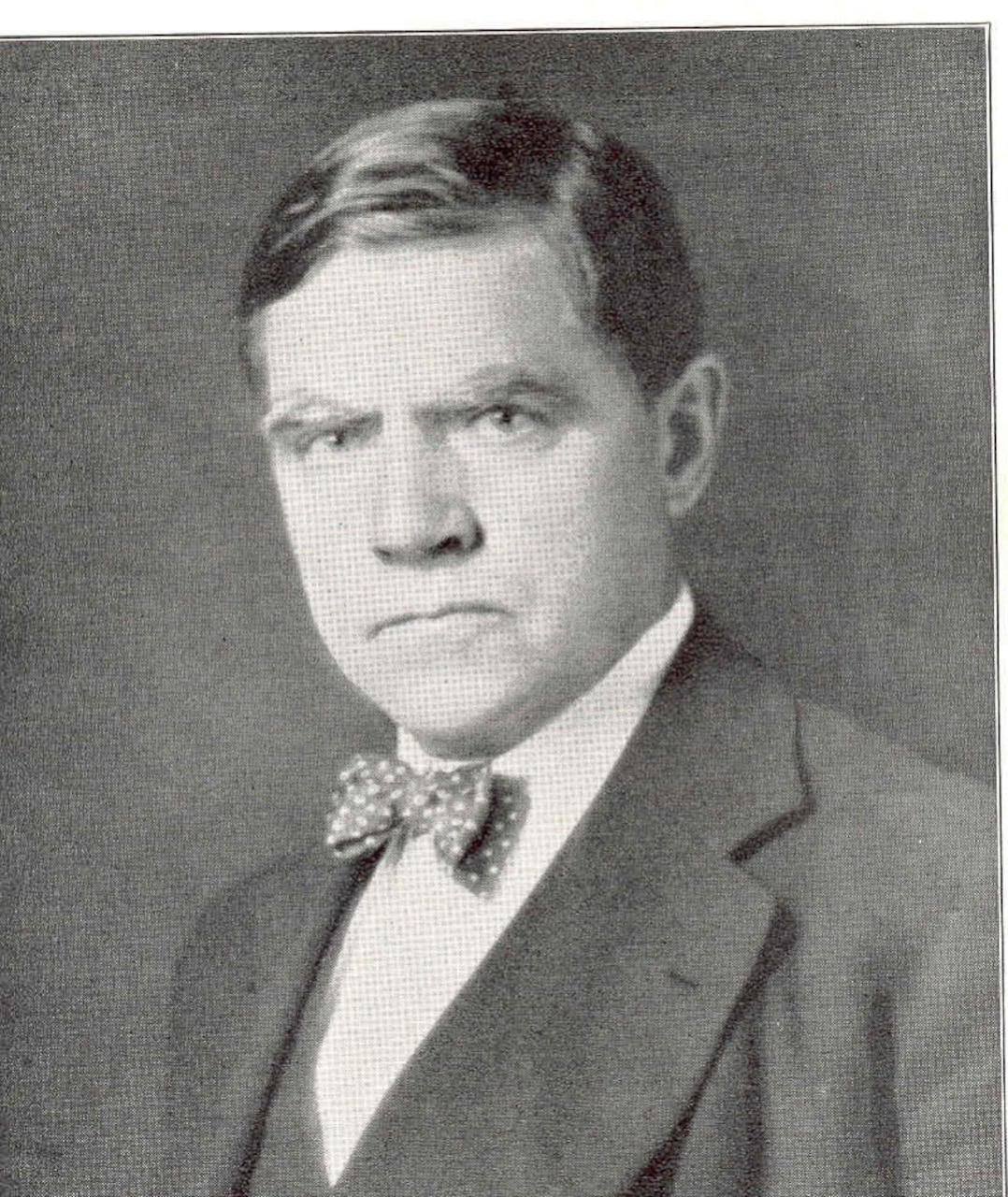 A man in suit and bowtie looks forward.