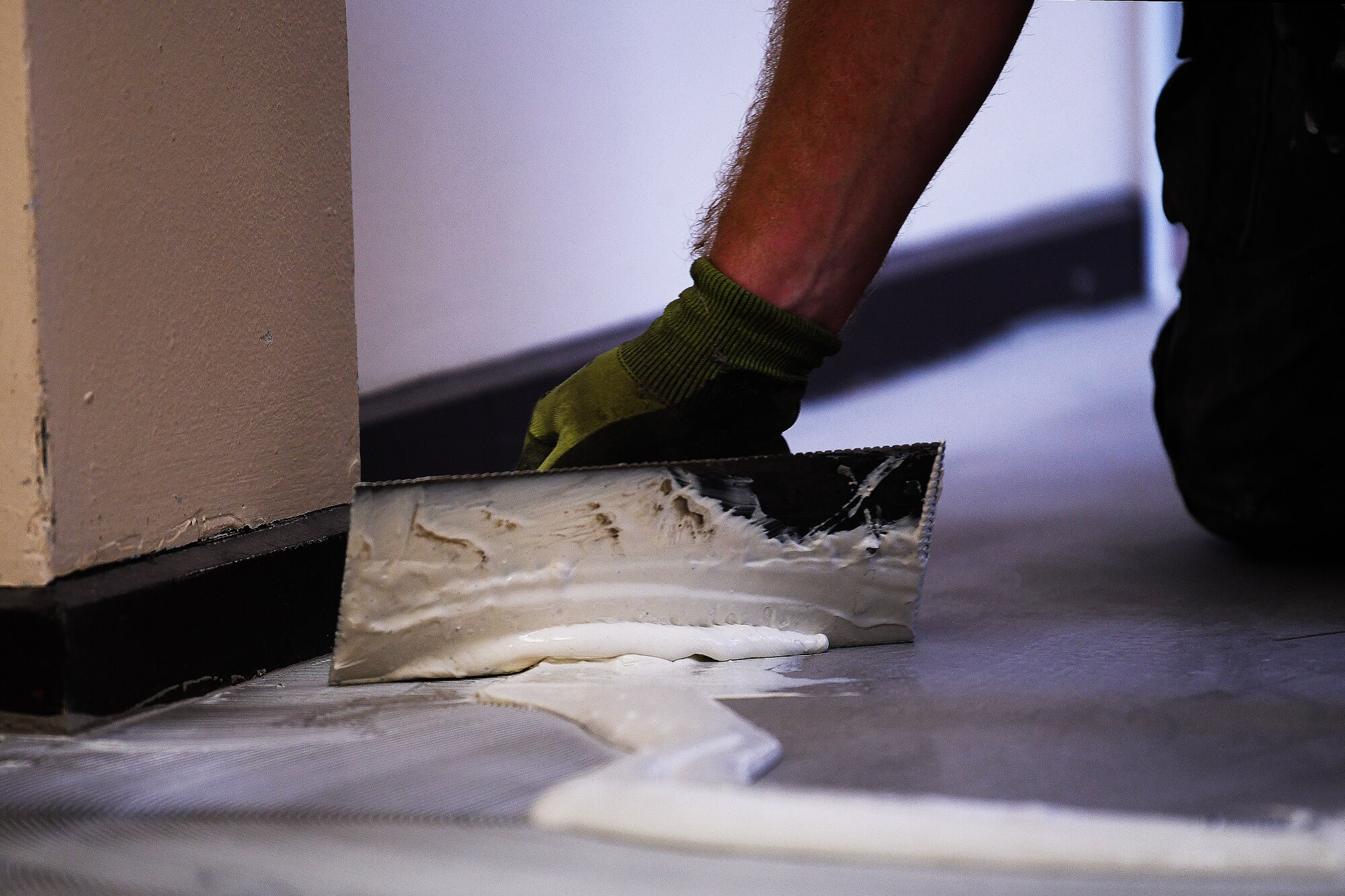 A base contractor spreads glue while installing new flooring at Lakenheath Elementary School, Royal Air Force Lakenheath, England, Aug. 11, 2020. The 48th Civil Engineer Squadron and base contractors, partnered with the Department of Defense Education Activity to ensure the RAFs Lakenheath, Feltwell, and Mildenhall community’s students safely returned to school. (U. S. Air Force photo by Senior Airman Shanice Williams-Jones)