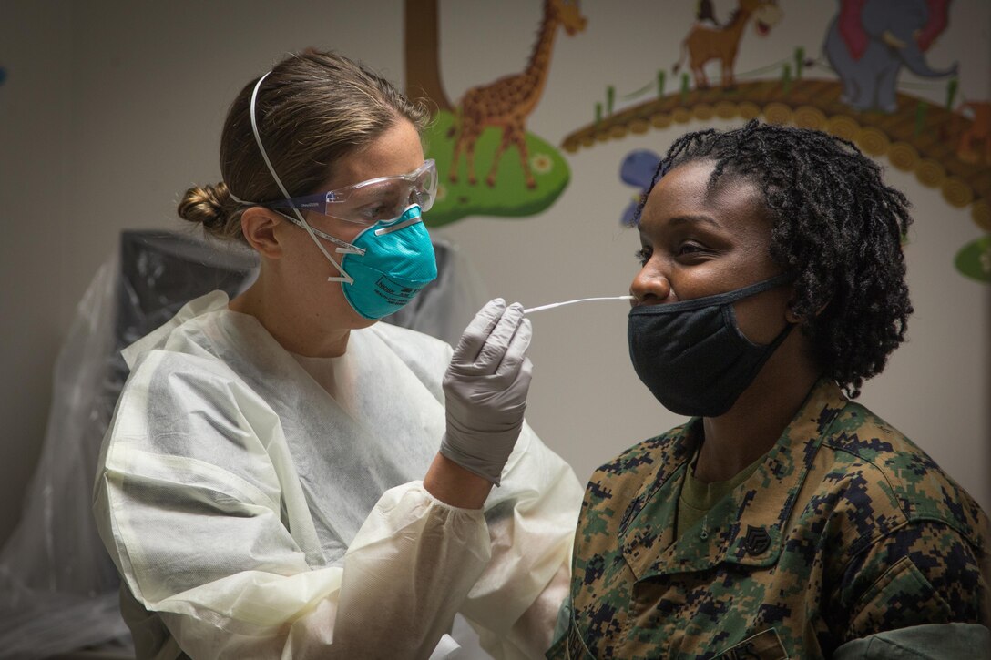 A nurse performs a COVID-19 test on a Marine.