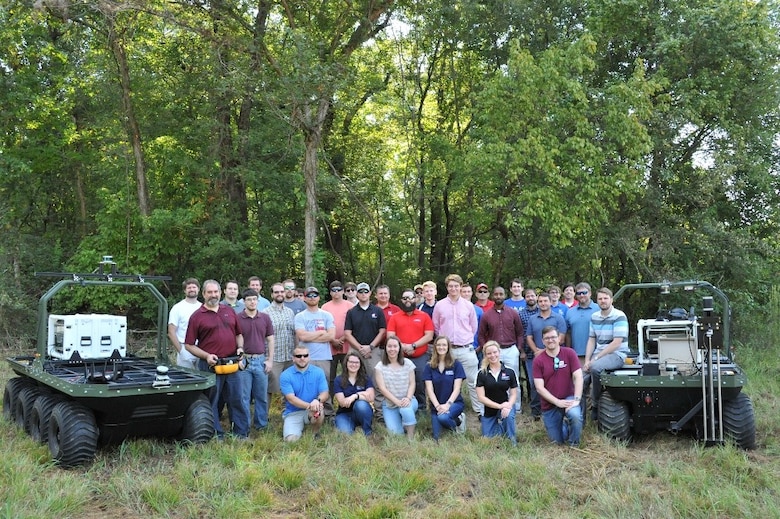 Researchers from the U.S. Army Engineer Research and Development Center’s Robotic Assessment of Closure Gates for Safe Entry and Robotic Engineer Operations project teams pose with the amphibious robotic vehicles prior to the outbreak of the COVID-19 pandemic. The team had to adjust strategies to a virtual platform using simulation software capabilities to meet mission requirements when the current pandemic environment halted real-world testing capabilities.