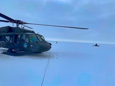 An Alaska Army National Guard UH-60 Black Hawk helicopter sits on packed snow about 25 miles east of Nome, Alaska, during a search and rescue mission for three Iditarod mushers March 20, 2020. The mushers and their dogs went through Bering Sea flood waters on the race trail and were wet and freezing. The aircrew transported two firefighter emergency medical technicians and Iditarod dog handlers to assist. The mushers were flown to Nome and transported to a local hospital. A local search and rescue team helped race dog handlers care for the sled team and returned them to Nome. (Courtesy photo)
