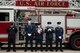 Service members stand in front of fire truck