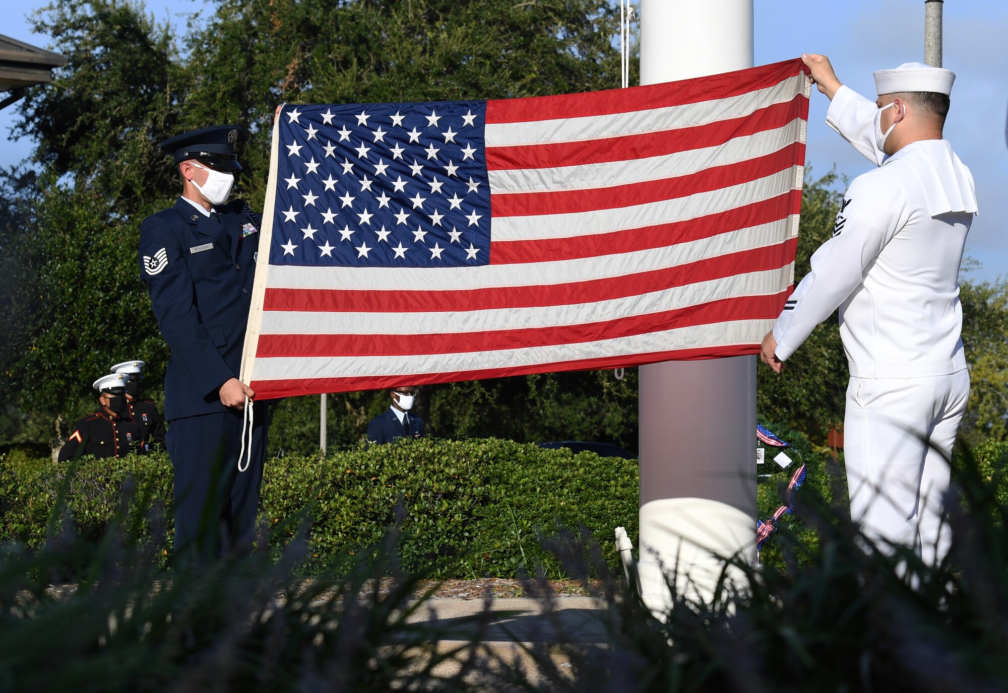 U.S. Air Force Tech. Sgt. Landon Spaulding, 81st Training Support Squadron military training leader, and U.S. Navy Aviation Electronics Technician 1st Class Javier Castoreno, Center for Naval Aviation Technical Training Unit Keesler instructor, display the U.S. flag during a 9/11 memorial ceremony hosted by the CNATTU Keesler in front of the 81st Training Wing headquarters building at Keesler Air Force Base, Mississippi, Sept. 11, 2020. The event honored those who lost their lives during the 9/11 attacks. (U.S. Air Force photo by Kemberly Groue)