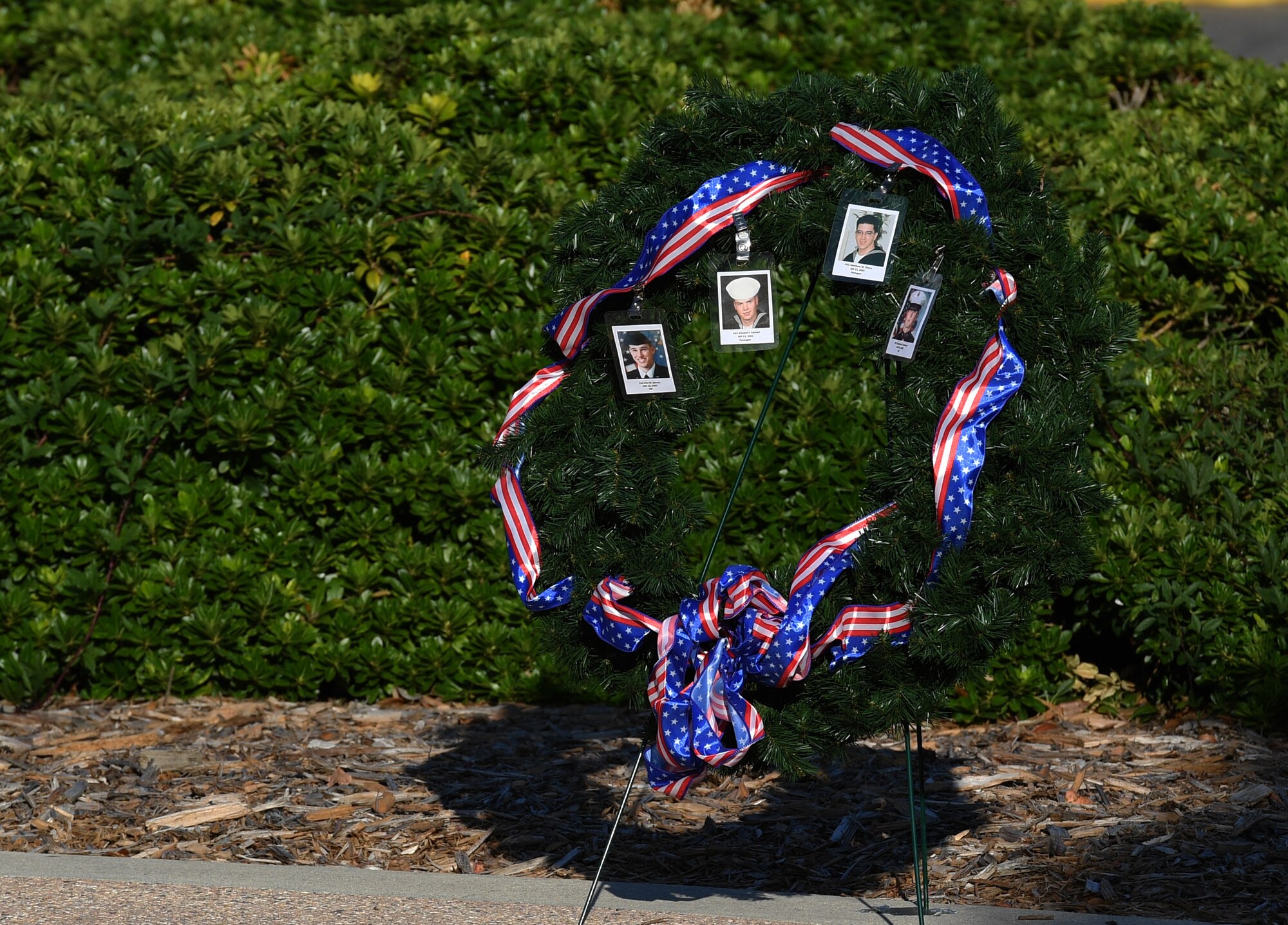 A wreath displaying photo identification cards of military members who lost their lives in the 9/11 attacks are displayed during a 9/11 memorial ceremony hosted by the Center for Naval Aviation Technical Training Unit Keesler in front of the 81st Training Wing headquarters building at Keesler Air Force Base, Mississippi, Sept. 11, 2020. The event honored those who lost their lives during the 9/11 attacks. (U.S. Air Force photo by Kemberly Groue)