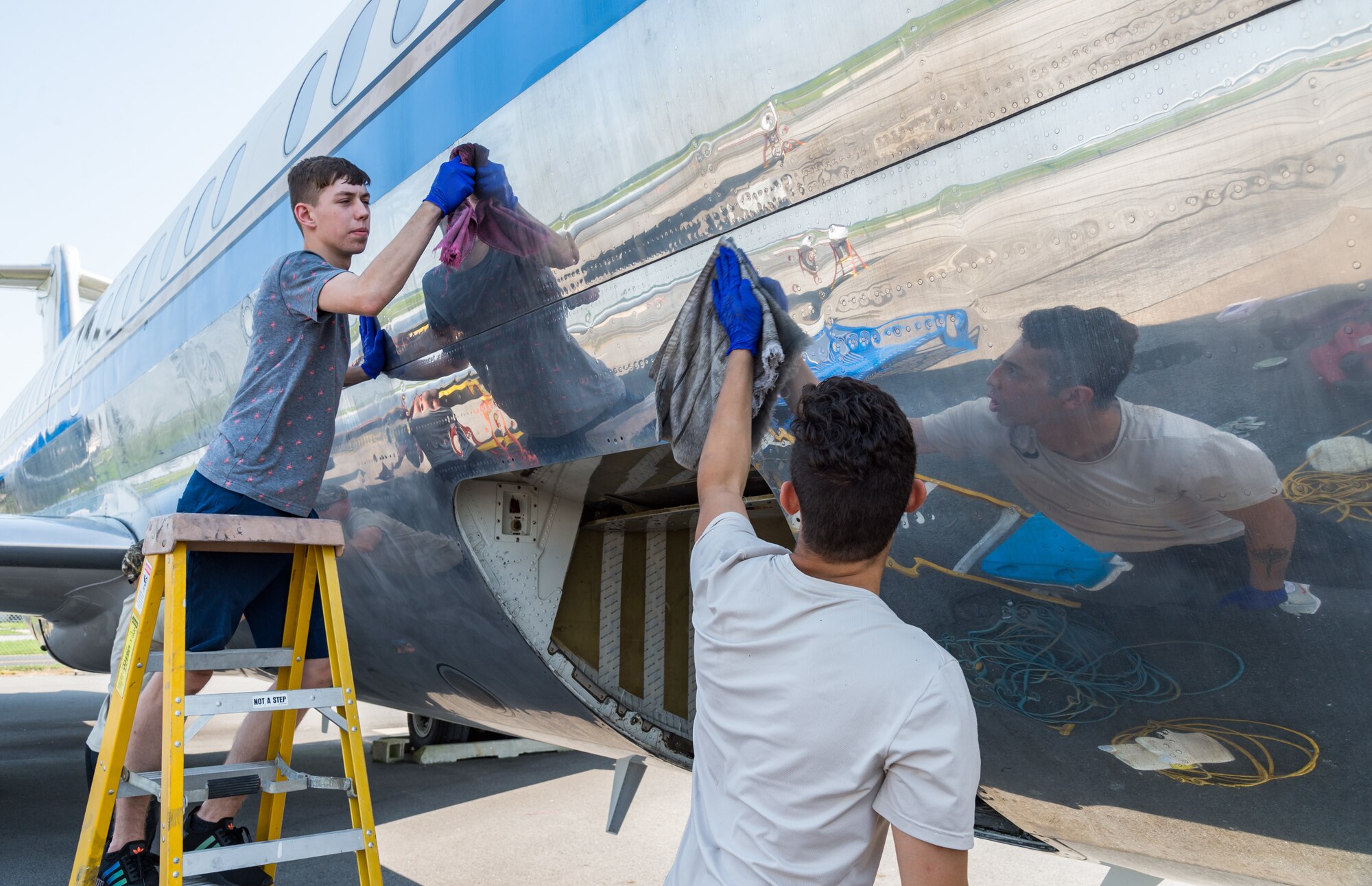 Airman 1st Class Weston Rose, aircraft hydraulic systems apprentice, and Senior Airman Kevin Aguilar, aircraft hydraulic systems journeyman, both from the 436th Maintenance Squadron aircraft hydraulic section, remove cleaning compound from the fuselage of a McDonnell Douglas VC-9C Aug. 25, 2020, at Air Mobility Command Museum on Dover Air Force Base, Delaware. Rose and Aguilar, along with other members of the hydraulic section, volunteered to strip, clean and polish the shiny aluminum skin of the aircraft formerly designated as Air Force Two. (U.S. Air Force photo by Roland Balik)